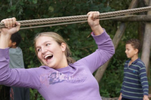 lachende vrouw op touwbrug tijdens teamuitje