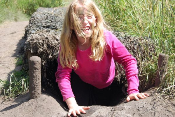 Meisje uit camotunnel tijdens actief kinderfeestje buiten in de natuur