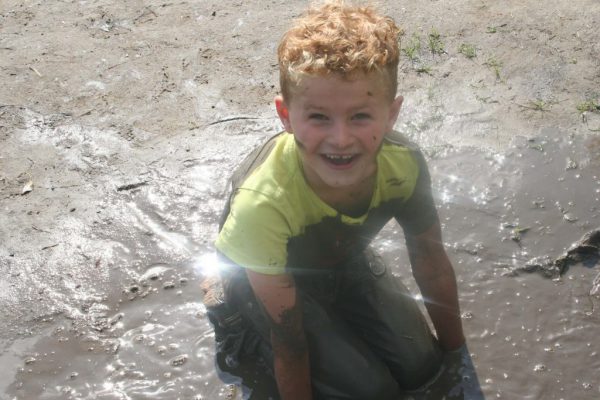 jongen in de modder bij kinderfeestje buiten in de natuur