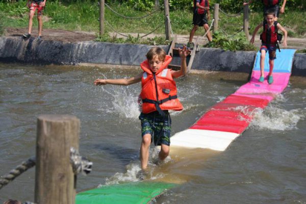 jongen met zwemvest loopt over watermat