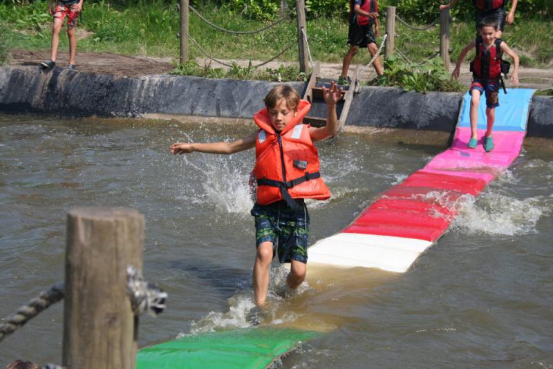 jongen met zwemvest loopt over watermat