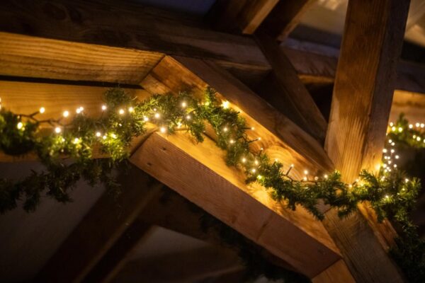 sfeervolle-winterborrel-decoratie-verlichting-almere - Outdoorpark SEC Almere Sfeervolle kerstverlichting en dennenboomguirlande op houten balken voor winterborrel in Almere