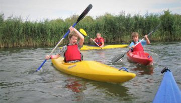 Kinderen in kayak tijdens watersport schoolreisje in Almere