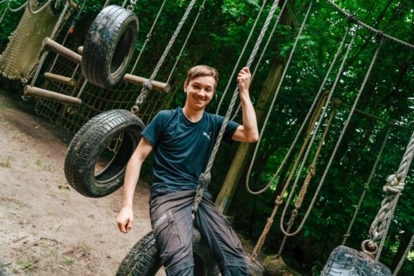 jonge-survival-deelnemer-banden-hindernisbaan - Outdoorpark SEC Almere Lachende jongen op banden hindernisbaan tijdens survival schoolreisje in Outdoorpark SEC Almere