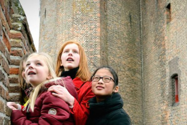 leerlingen voor de muur van kasteel Muiderslot