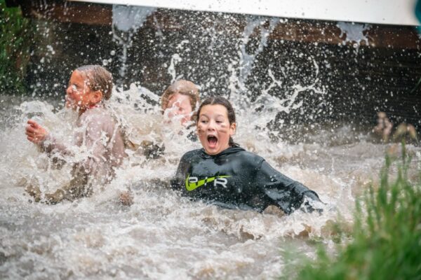 kinderen-spetteren-modderwater-survival-schoolreisje - Outdoorpark SEC Almere Kinderen spetteren enthousiast in modderig water tijdens survival schoolreisje