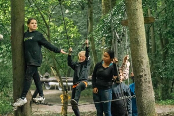 kinderen-touwbrug-parcours-survival-schoolreisje - Outdoorpark SEC Almere Kinderen balanceren op een touwbrug in het bos tijdens een survival schoolreisje