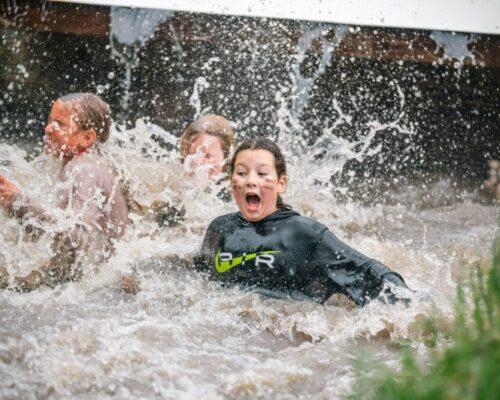 schoolreisje-waterhindernisbaan-survival-kinderen-almere - Outdoorpark SEC Almere Kinderen spatten enthousiast door een waterhindernisbaan tijdens een survival schoolreisje bij Outdoorpark SEC Almere, vol actie en plezier.