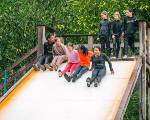 schoolreisje-waterslide-survival-almere - Outdoorpark SEC Almere Children on a thrilling waterslide during a survival school trip at Outdoorpark SEC Almere, enjoying active outdoor fun.