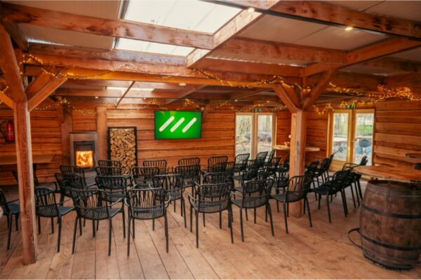 Sfeervolle Boshut vergaderzaal in presentatie-opstelling met open haard en scherm bij Outdoorpark Almere