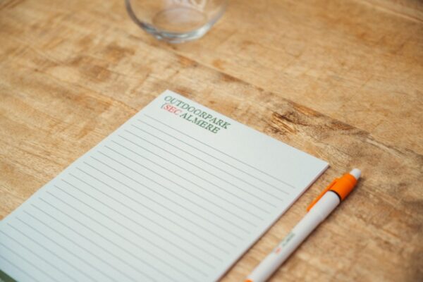 Close-up of an Outdoorpark Almere branded notepad and pen on a wooden meeting table.