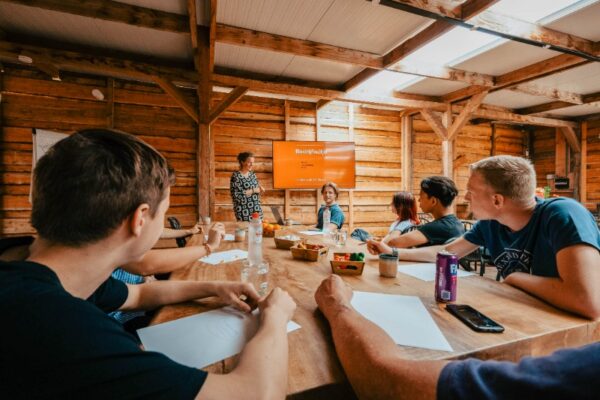 Group of professionals in a meeting discussing a company outing in a wooden, natural meeting room at Outdoorpark Almere.